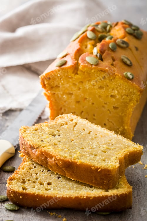 Preview: Sliced pumpkin bread loaf decorated with pepitas on rustic table