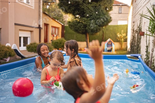Preview: Children playing joyfully in a backyard swimming pool during summer