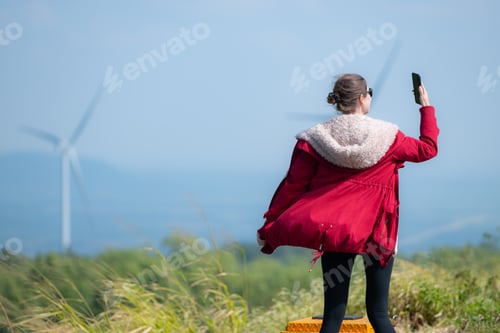 Preview: On the background of windmills, A young woman in a red jacket is enjoying her winter vacation.