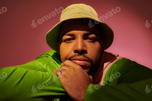 Preview: handsome stylish man in green panama with hands near face looking at camera, fashion concept