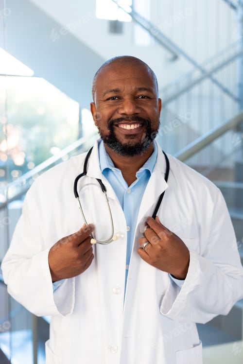 Preview: Vertical portrait of smiling african american male doctor in hospital corridor