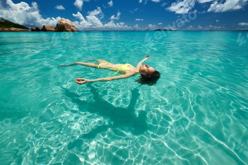 Preview: Woman In Bikini Lying On Water At Tropical Beach