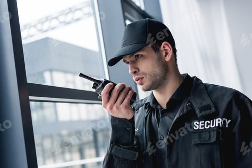 Preview: cropped view of guard in uniform talking on walkie-talkie and looking away