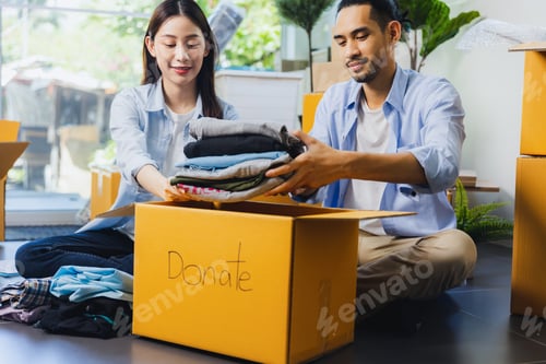 Preview: Donation Concept. love couple Woman and man put clothes to donate Box with full of Clothes