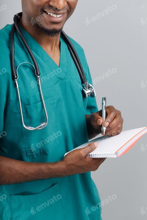 Preview: African-American doctor writing medical prescription in blue uniform standing against grey backgroun