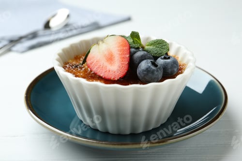 Preview: Delicious creme brulee with berries and mint in bowl on white wooden table, closeup