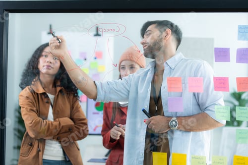 Vista previa: Multiethnic young business people brainstorming on a project by writing on the glass wall