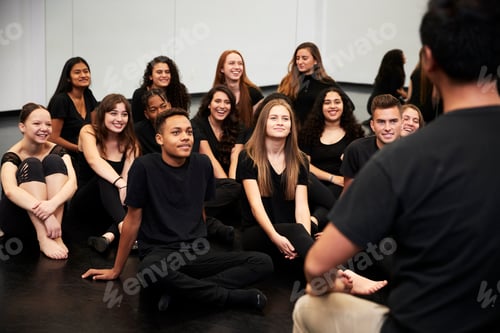 Preview: Teacher At Performing Arts School Talking To Students Sitting On Floor In Rehearsal Studio