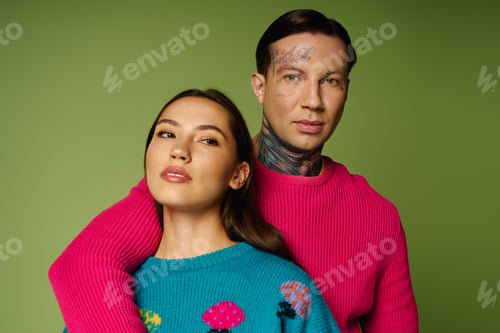 Preview: Young couple enjoying a playful moment against a vibrant green background in trendy outfits