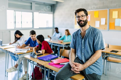 Preview: Portrait of young bearded male teacher sitting at high school table