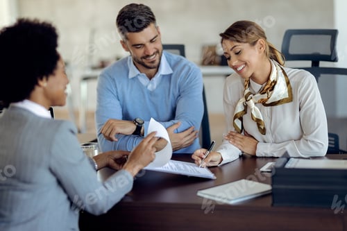 Preview: Happy couple signing an agreement with real estate agent in the office.