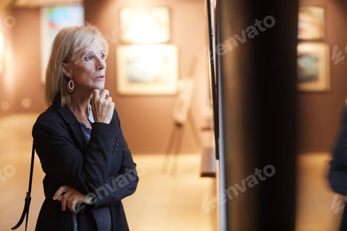 Preview: Senior Woman Looking at Paintings in Art Gallery