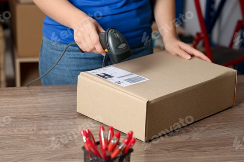 Preview: Post office worker with scanner reading parcel barcode at counter, closeup
