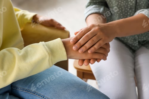 Preview: Psychotherapist holding patient's hand in office, closeup