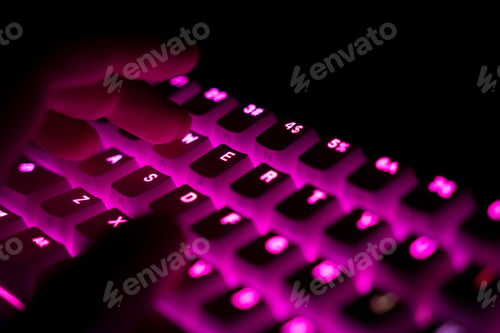 Preview: side view of fingers typing on illuminated RGB keyboard in the dark