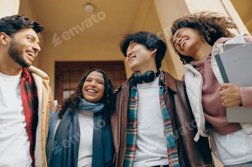 Preview: Smiling students talking and laughing together outdoor standing near campus and holding books