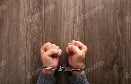 Preview: Arrested criminal hands locked in handcuffs.