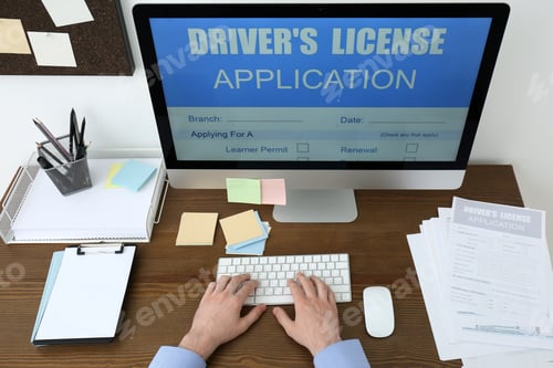 Preview: Man using computer to fill driver's license application form at table in office, closeup