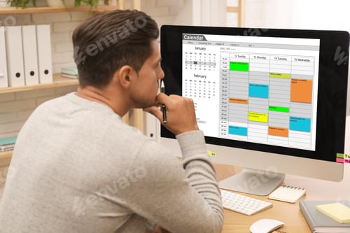 Preview: Handsome man using calendar app on computer in office