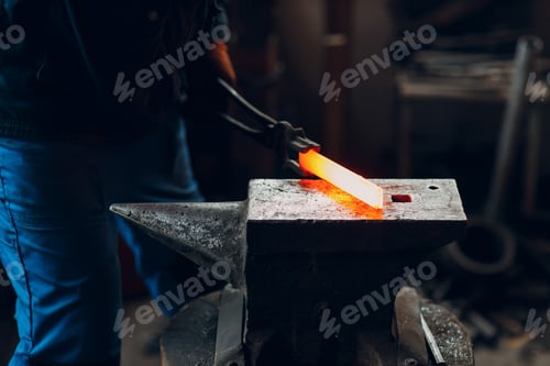 Preview: Blacksmith forges and makes metal detail with hammer and anvil at forge.