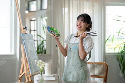 Preview: Portrait of a young female artist working on an abstract acrylic canvas painting in an art painting