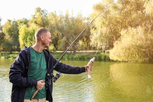 Preview: Man with rod fishing at riverside on sunny day. Recreational activity