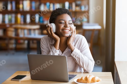 Preview: Black woman listening to music with headset, laptop in cafe