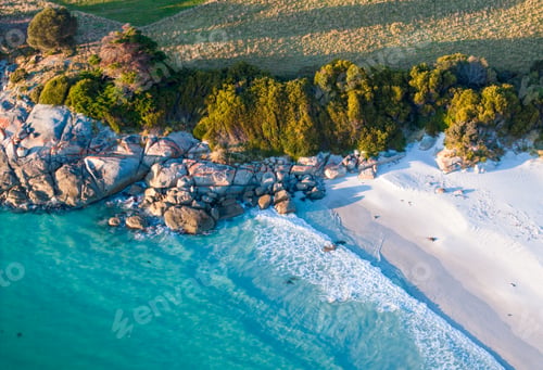 Preview: Aerial shot of a beautiful beach with turquoise waters, green trees, and rocks