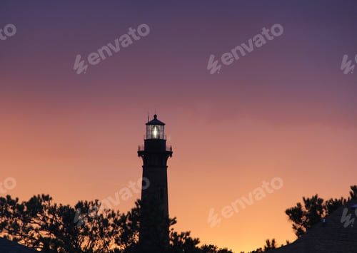 Preview: Beautiful sunset with lighthouse & trees silhouettes with purplish orange ski in background