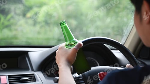 Preview: Man driving a car while holding a bottle of beer. Driving under the influence.