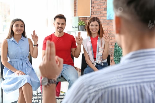 Preview: Group of young people learning sign language with teacher indoors