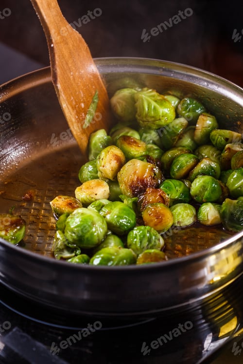 Preview: young woman fries Brussels sprouts on a frying pan