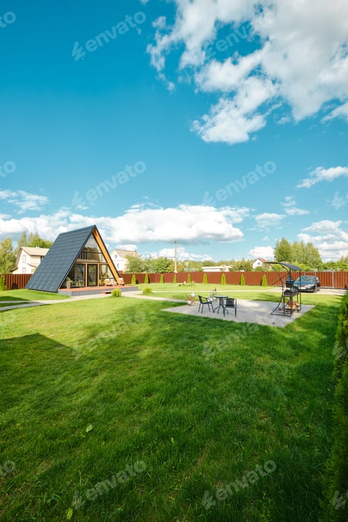 Preview: Cozy A-frame house in a sunny backyard with a garden and patio, surrounded by greenery