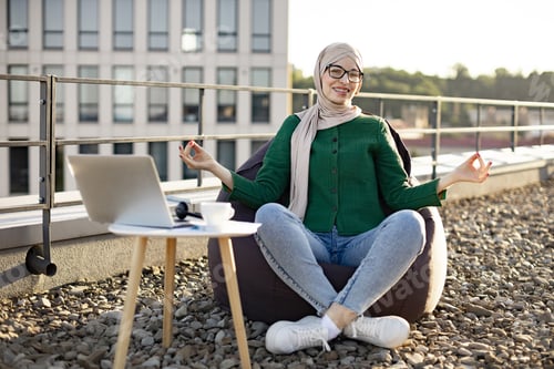Preview: Muslim woman with gyan mudra smiling in bean bag on roof
