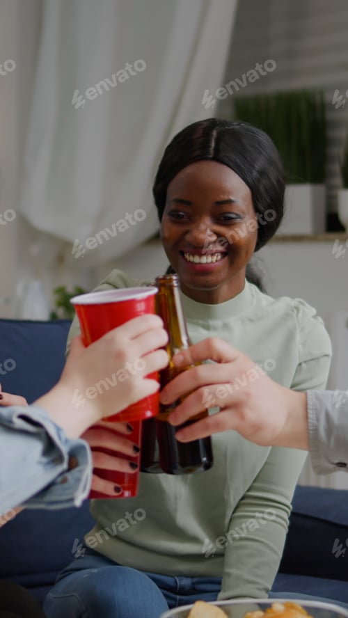Preview: Afro american woman talking with her friends holding beer bottle