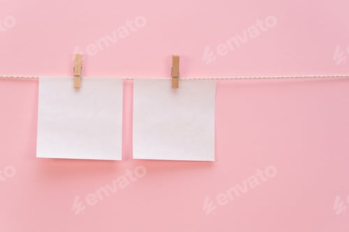 Preview: two clean empty white stickers hanging with a clothespin on a rope on a pink color background