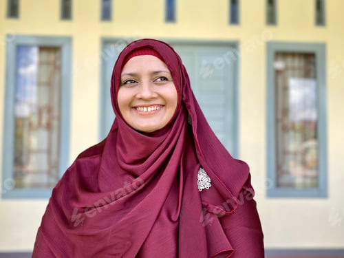 Preview: Woman in red hijab smiling looking at the terrace of the house