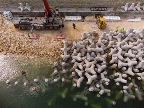 Preview: Aerial view of breakwater construction. Bulldozer and crane on a pile of boulders in the sea