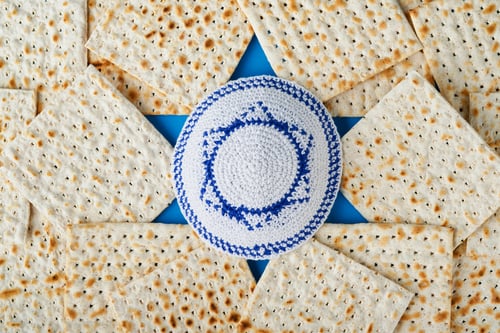 Preview: Passover celebration concept. Blue Star of David made from matzah, white and yellow roses, kippah an