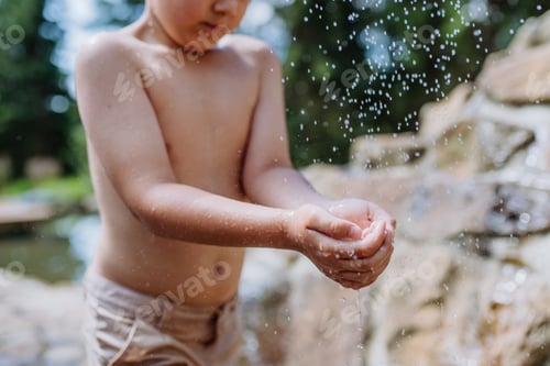 Preview: Close up of little boy playing outside with water, splashing.