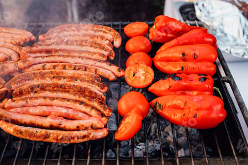 Preview: sausage with vegetables grilling over a barbecue fire on a hot day during the summer vacation.