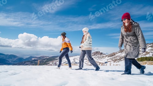 Preview: Three women hiking in snowy mountain landscape on sunny winter day