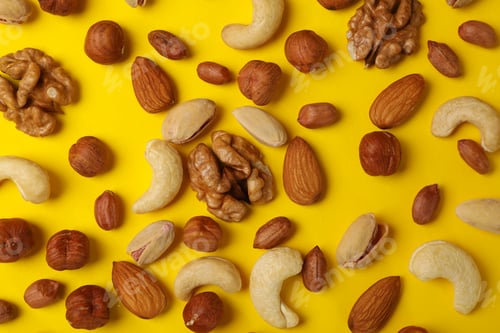 Preview: Different nuts on yellow background. Vitamin food