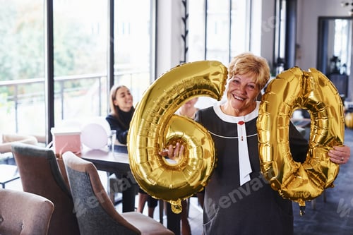 Preview: Senior woman with family and friends celebrating a birthday indoors