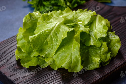 Preview: Salad, parsley and dill on a dark cutting board against a blue concrete background