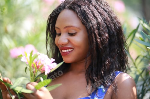 Preview: Cheerful young Afro American woman standing in tropical garden.