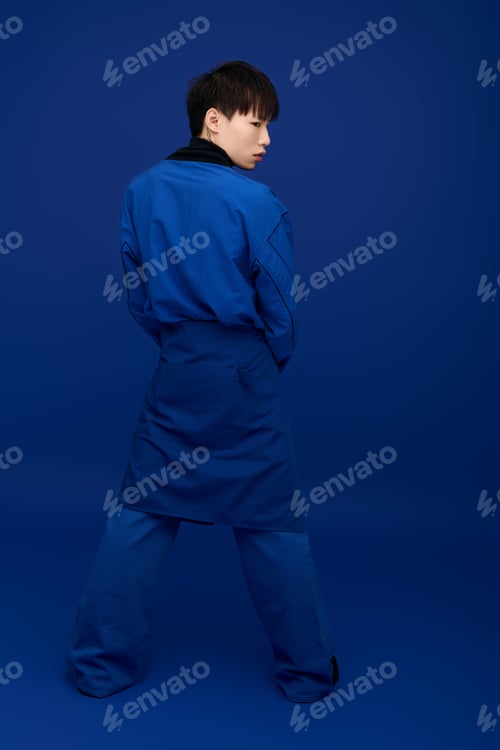Preview: Captivating young asian man in blue attire poses against a vibrant blue backdrop