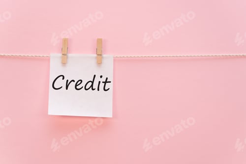 Preview: sticker with the inscription Credit hangs with a clothespin on a rope on a pink background