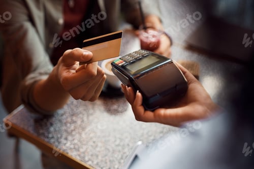 Preview: Close up of man using credit card while paying in a cafe.