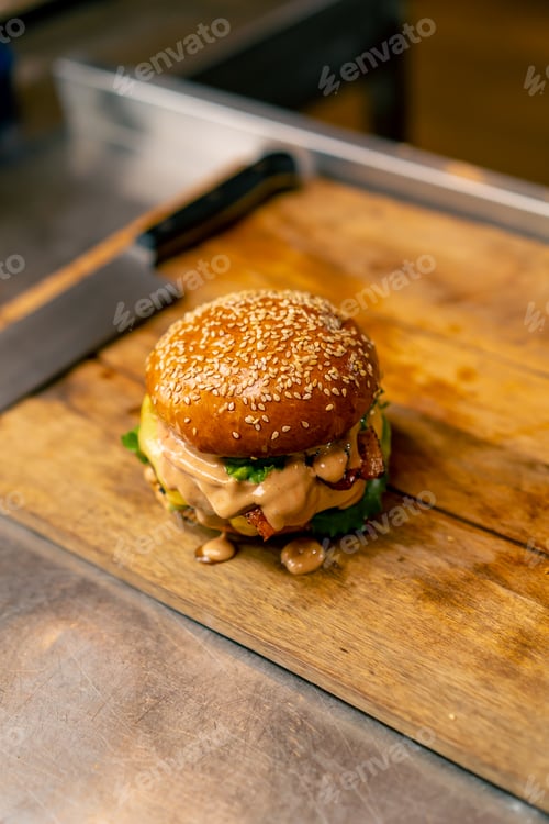 Preview: A close-up of a burger with beef patty with vegetables and cheese cooked in the professional kitchen